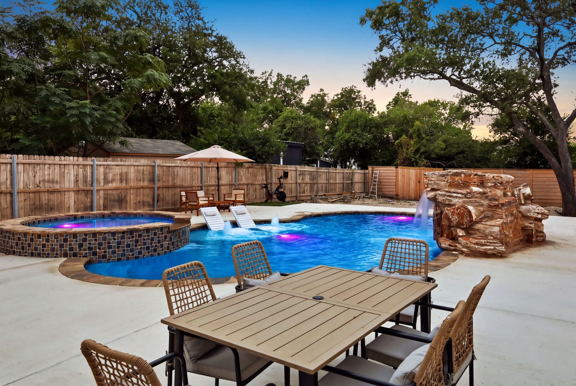 Poolside patio dining set beside the spa and rock waterfall