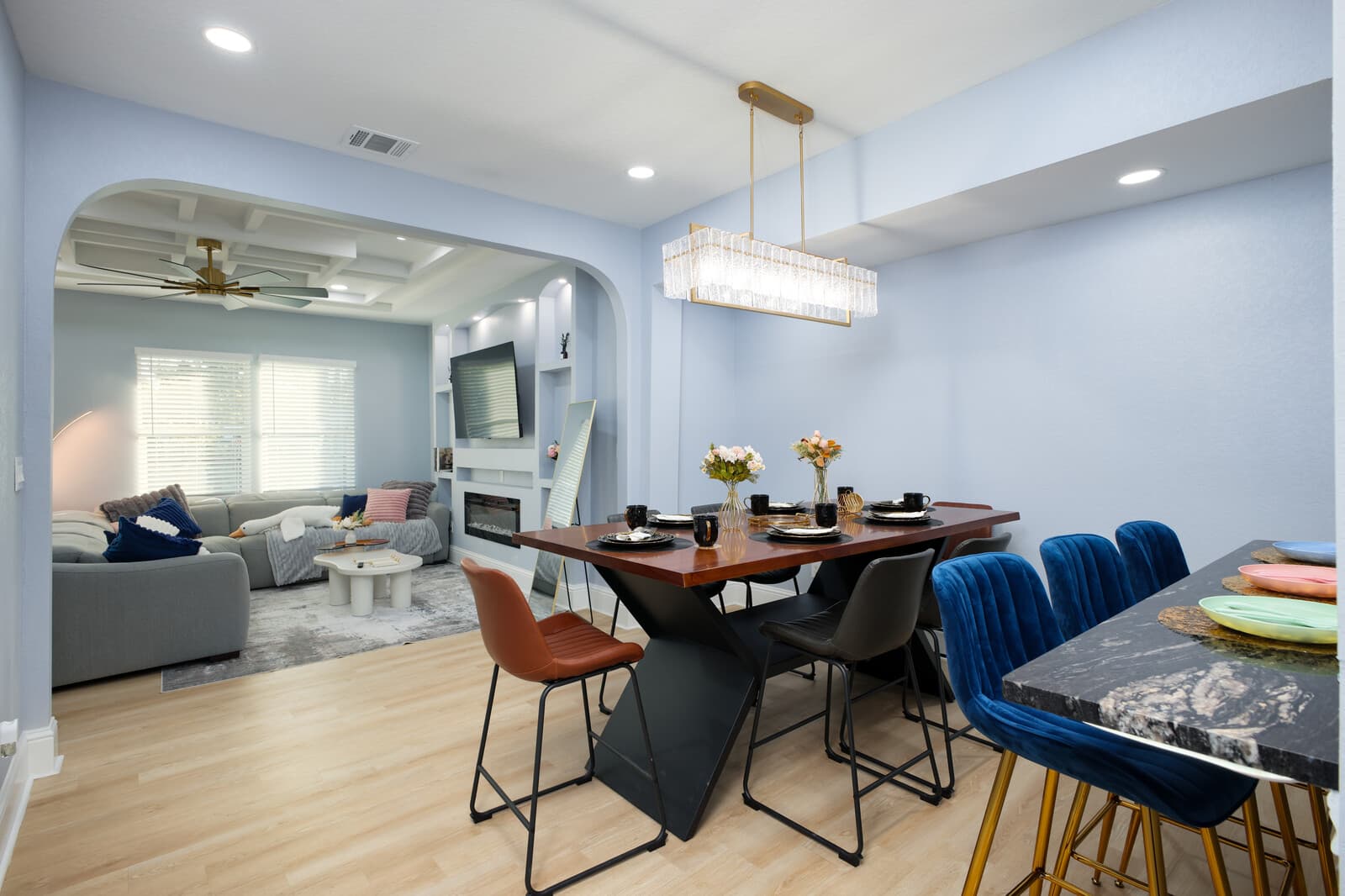 Dining area open to the living room, with a linear glass pendant over the table