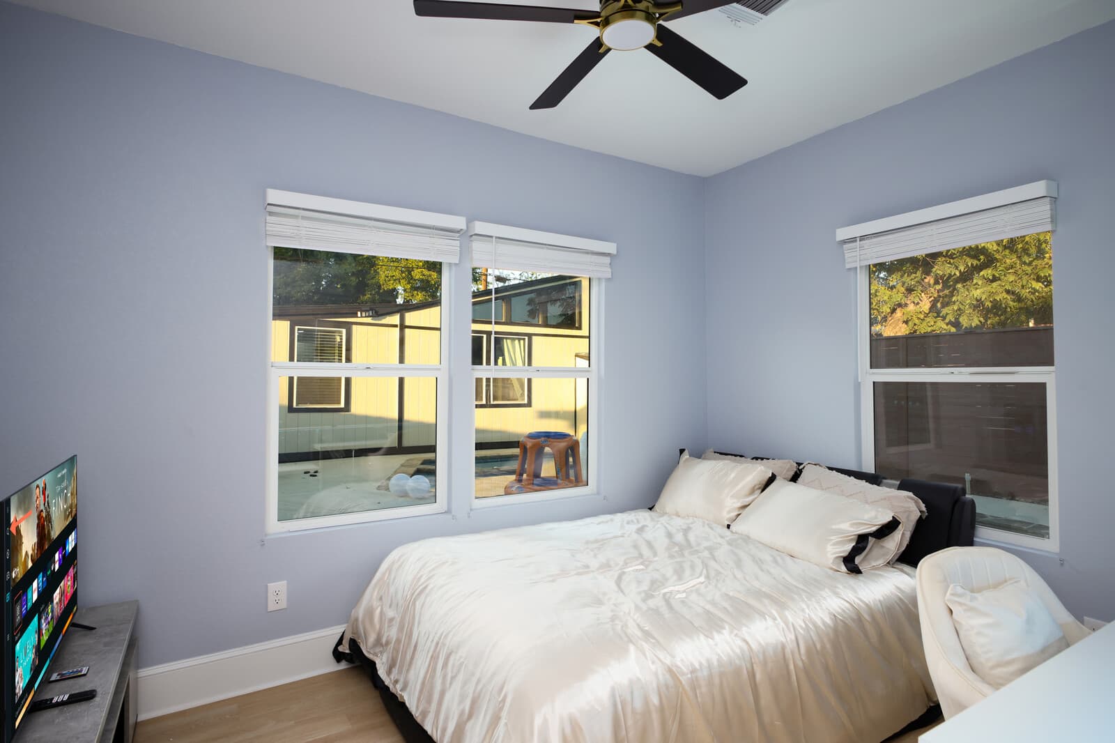 Guest bedroom with two windows, a ceiling fan and light oak flooring